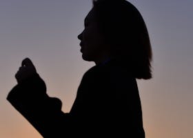 A silhouette of a woman captured against a colorful sunset sky, conveying serenity.